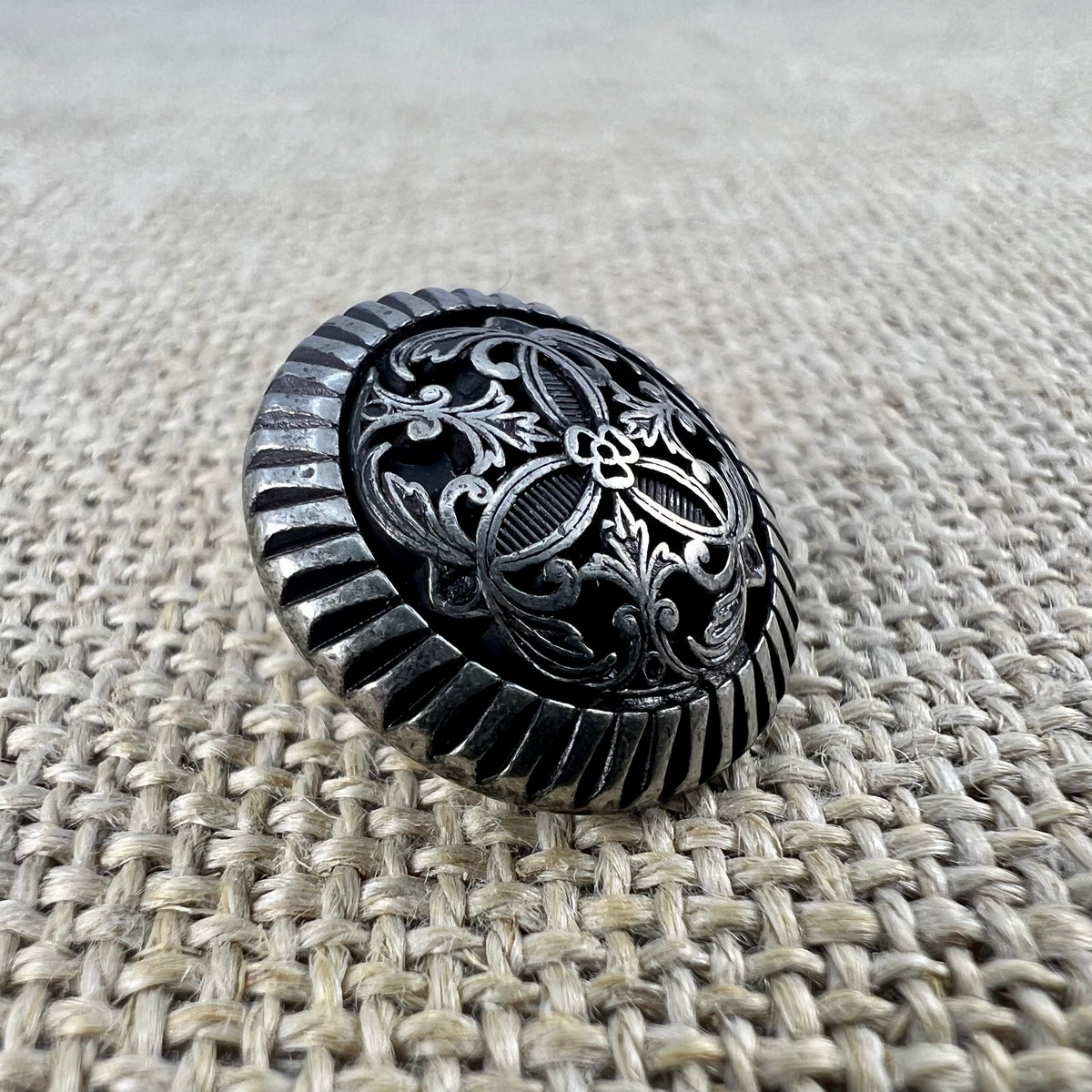Filigraner Messingknopf in Altsilber mit Blume in der Mitte und Ranken