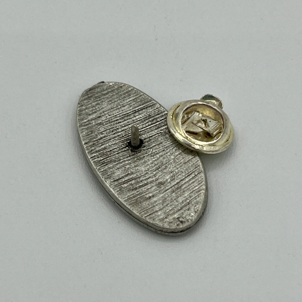 Ovale Anstecknadel mit Notenschlüssel auf geriffeltem Grund im Antik-Silber-Look