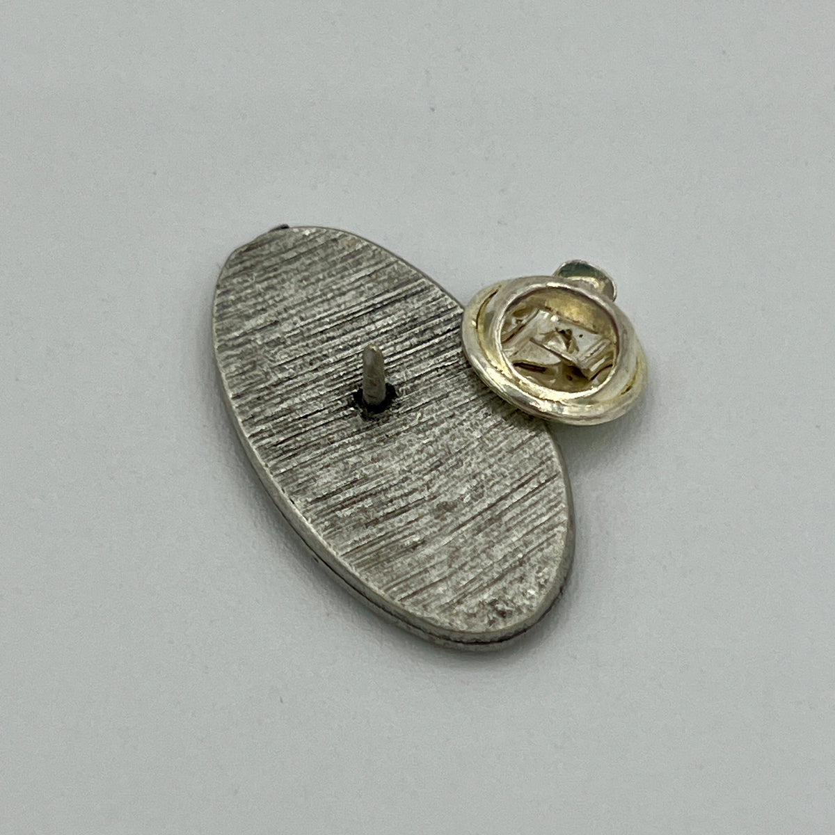Ovale Anstecknadel mit Notenschlüssel auf geriffeltem Grund im Antik-Silber-Look
