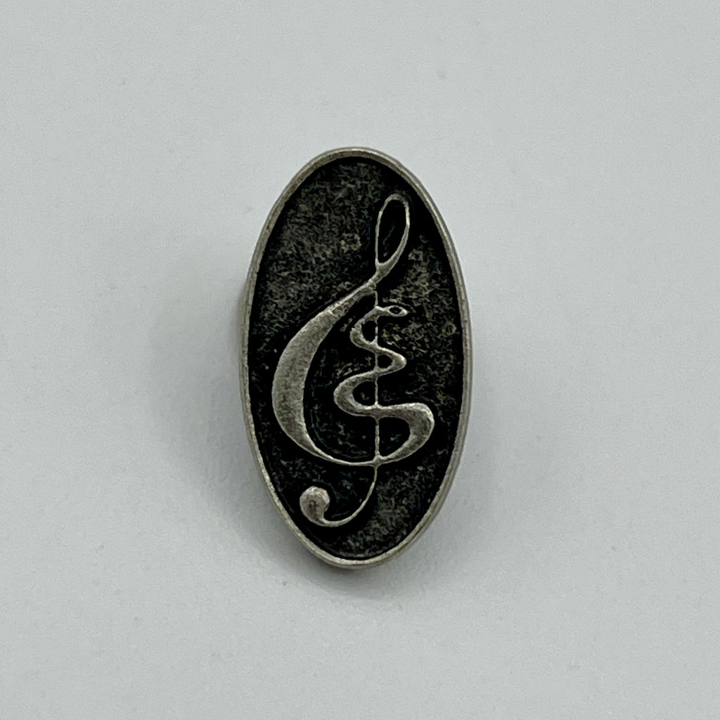 Kleine ovale Anstecknadel mit Notenschlüssel auf schwarzem Grund im Antik-Silber-Look